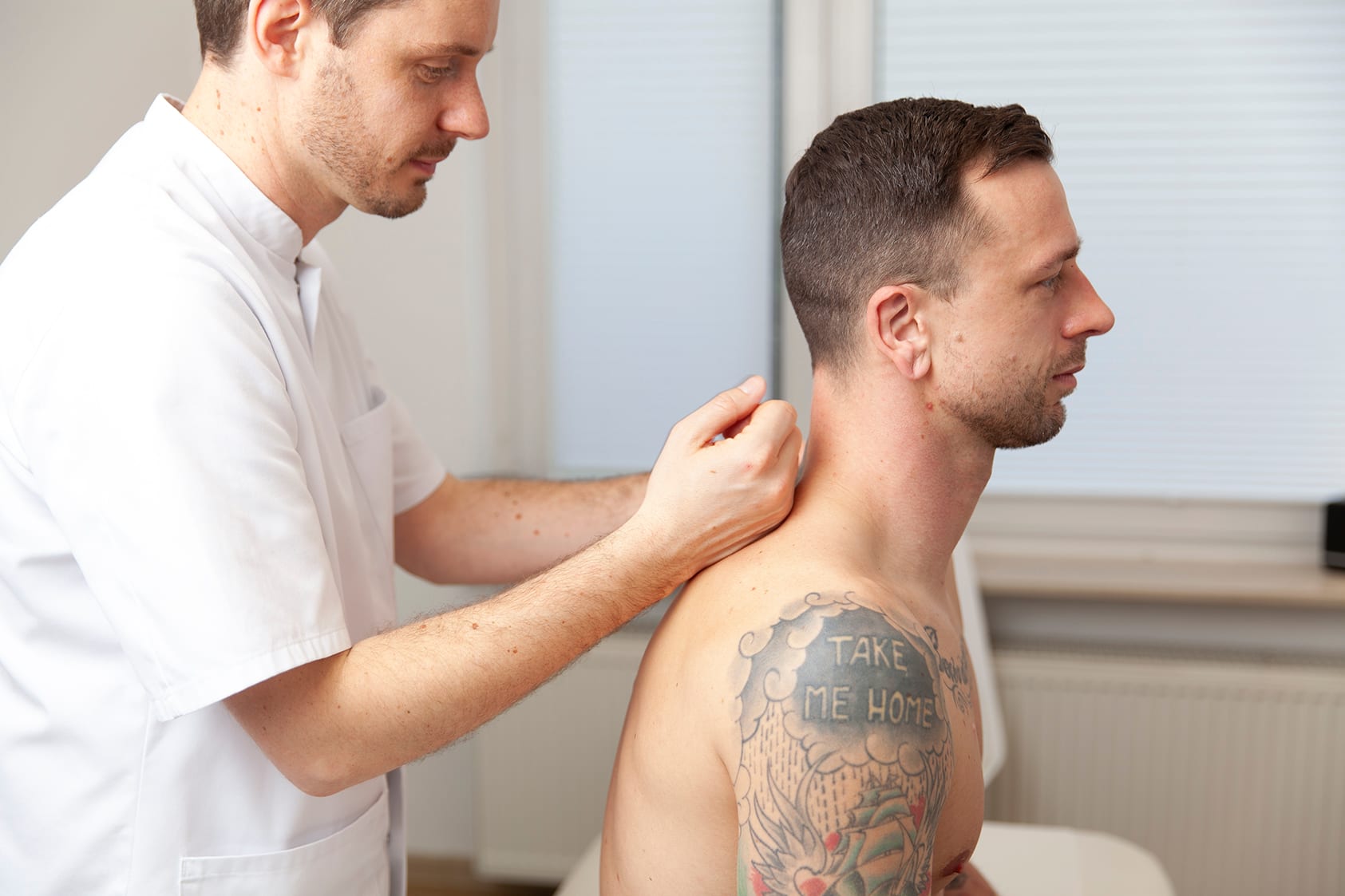 Im Behandlungsraum massiert Heilpraktiker Rick Putzer einen Patienten im Nackenbereich.