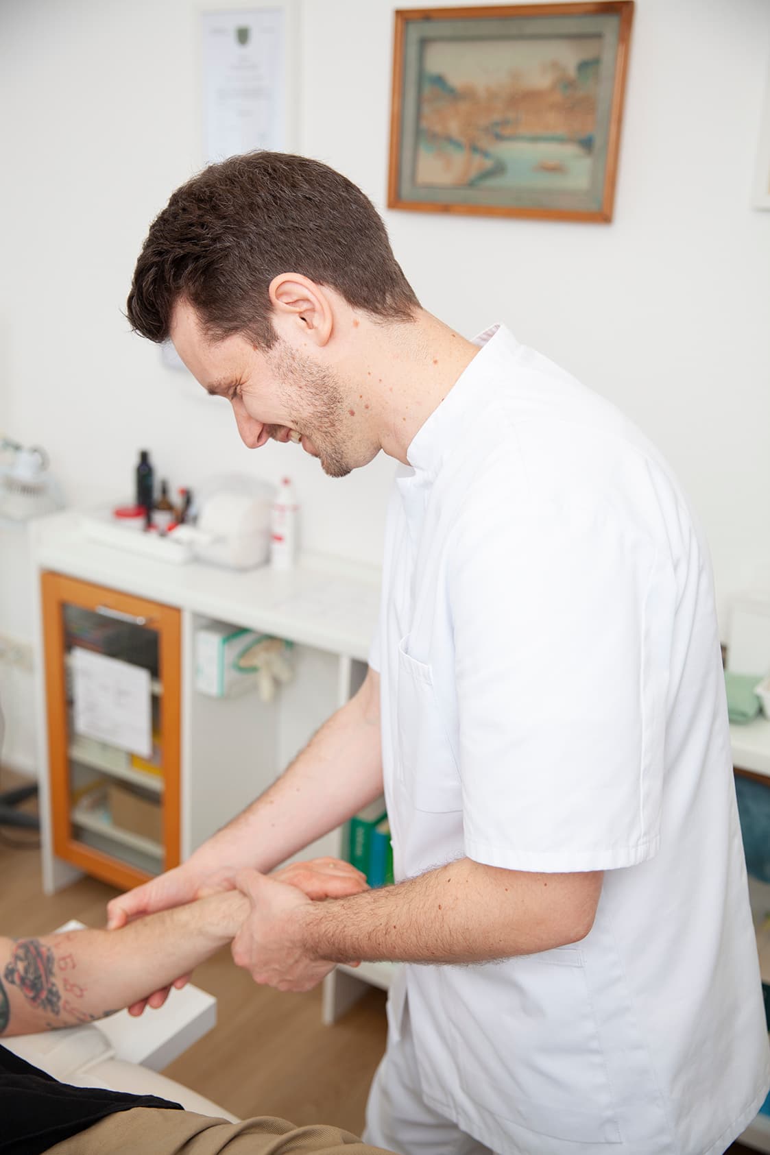 Heilpraktiker Rick Putzer bei der Palpation (Tastung) der Leitbahnen am Unterarm eines Patienten.