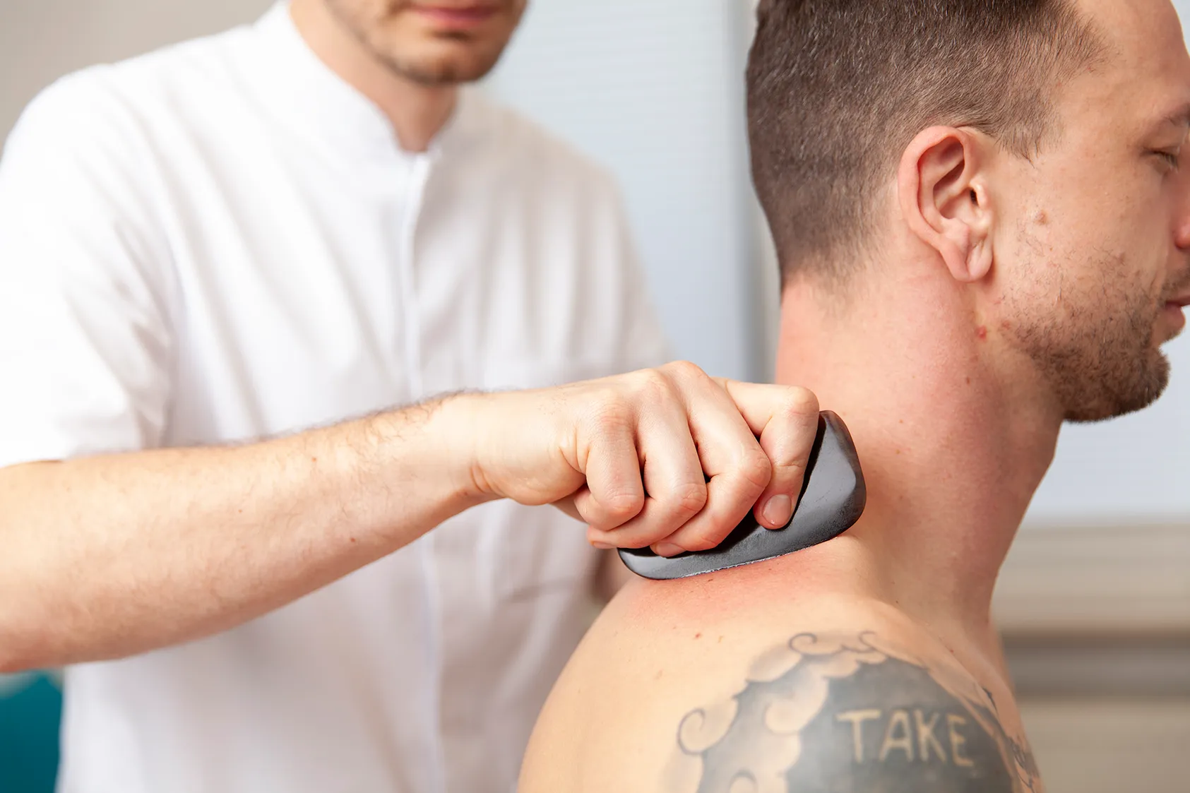 Heilpraktiker wendet Gua Sha Verfahren bei Patienten an