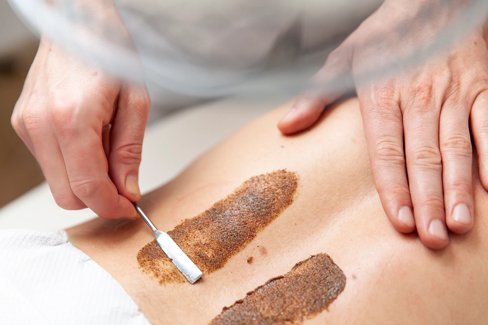 Heilpraktiker Rick Putzer trägt eine Kräuterauflage am unteren Rücken eines Patienten auf.