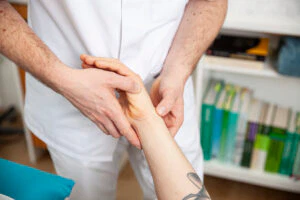 Heilpraktiker Rick Putzer bei der Leitbahnpalpation (Tastung) am Handgelenk eines Patienten.